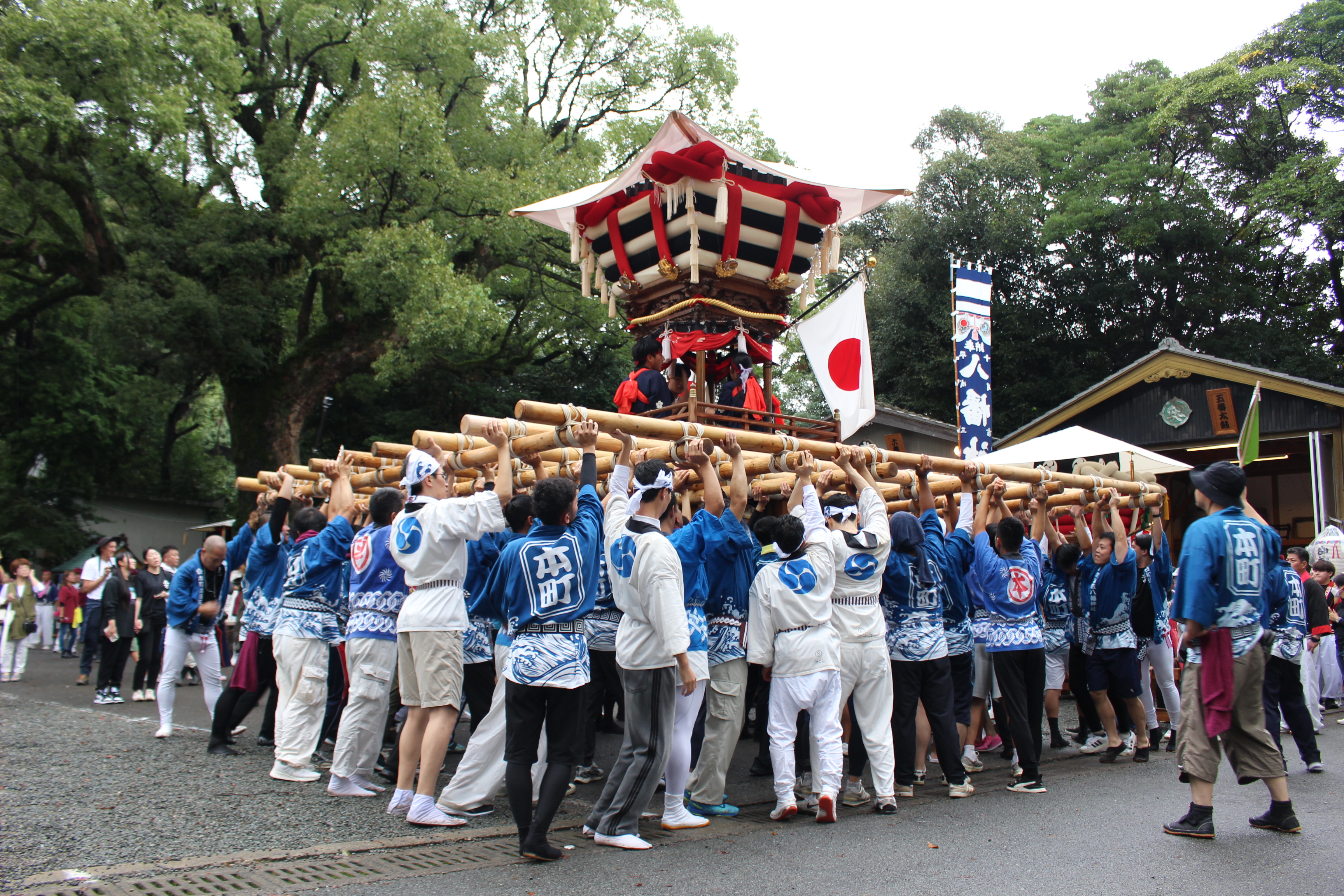神社のそばで神輿を掲げる様子