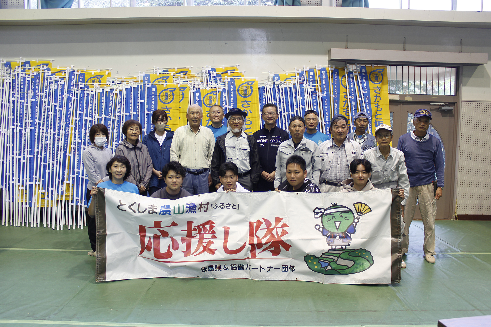 横断幕を持ち18名が集まった写真