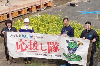 応援し隊の横断幕と応援してくださった方と菜の花との撮影です